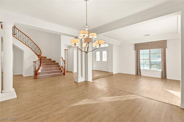 unfurnished dining area featuring crown molding, wood finished floors, stairs, and decorative columns