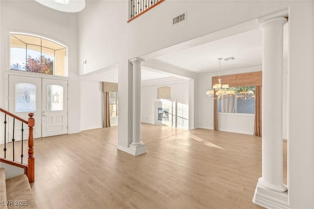 foyer with visible vents, ornate columns, light wood-style flooring, stairs, and a wealth of natural light