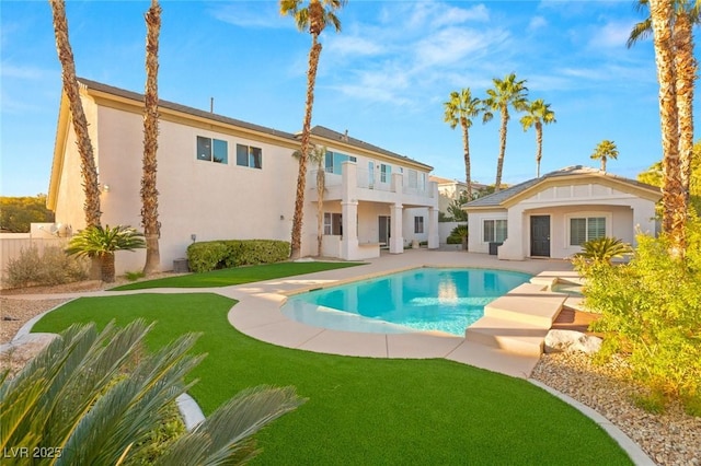 rear view of house featuring an outbuilding, a balcony, a patio, a fenced in pool, and stucco siding