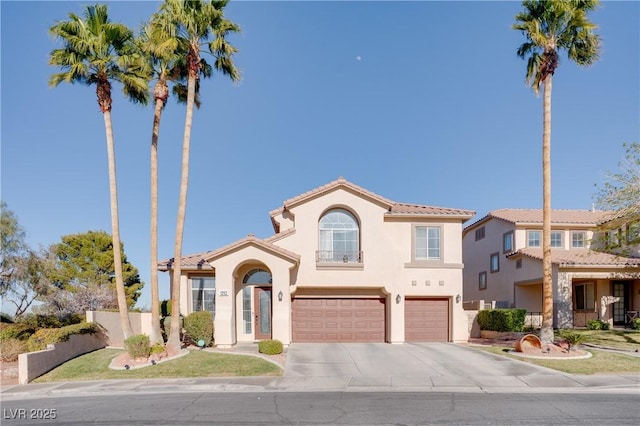 mediterranean / spanish house with fence, a tile roof, stucco siding, a garage, and driveway