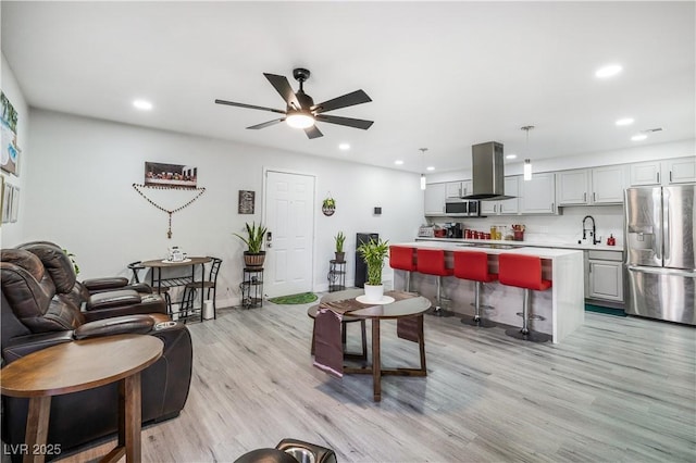 living area with recessed lighting, light wood-style floors, and ceiling fan