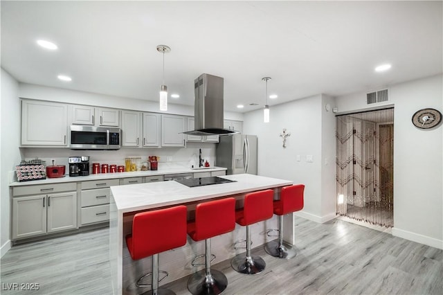 kitchen with visible vents, light countertops, appliances with stainless steel finishes, island exhaust hood, and light wood-style floors