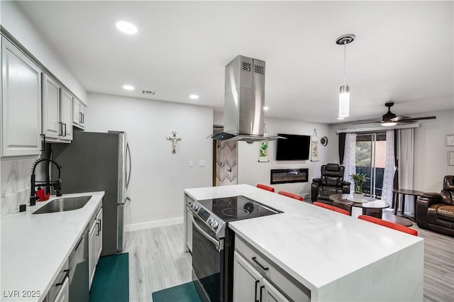 kitchen featuring visible vents, a sink, stainless steel appliances, open floor plan, and island range hood