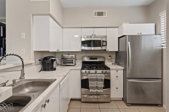 kitchen with visible vents, appliances with stainless steel finishes, light tile patterned flooring, white cabinets, and a sink