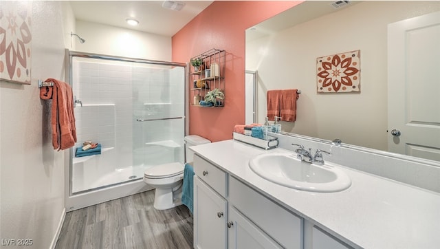 bathroom featuring a stall shower, toilet, vanity, and wood finished floors