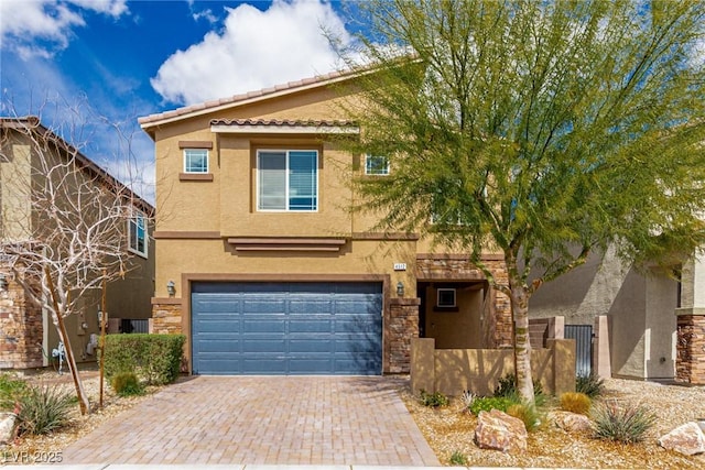 view of front of property with a tile roof, stucco siding, decorative driveway, stone siding, and an attached garage