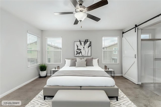 bedroom with a barn door, multiple windows, and baseboards