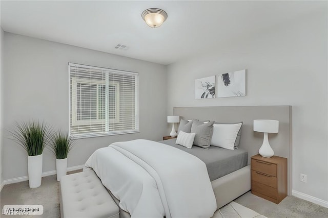 bedroom featuring visible vents, light carpet, and baseboards