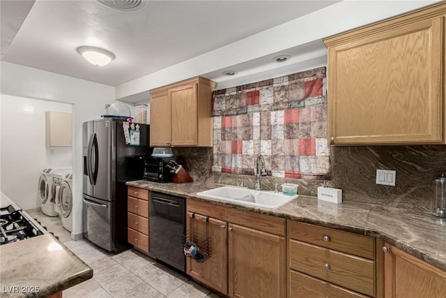 kitchen with washing machine and clothes dryer, a sink, decorative backsplash, dishwasher, and stainless steel fridge