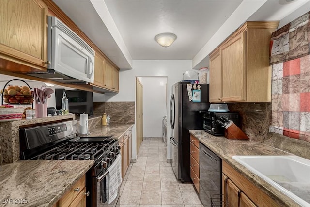 kitchen featuring tasteful backsplash, a toaster, light tile patterned floors, appliances with stainless steel finishes, and a sink