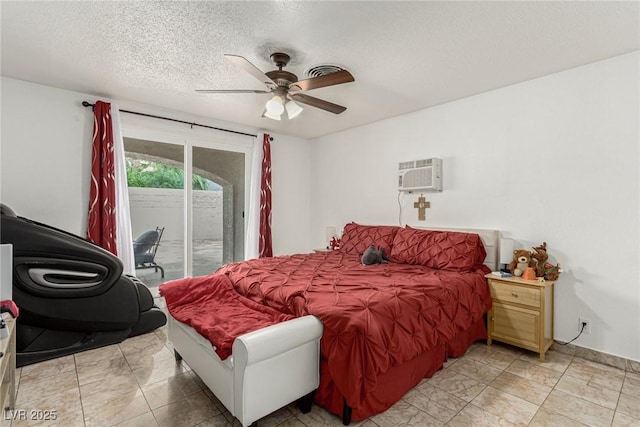 bedroom featuring access to exterior, a textured ceiling, a wall mounted air conditioner, and a ceiling fan