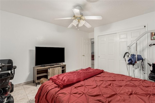 bedroom featuring a closet, baseboards, marble finish floor, and a ceiling fan