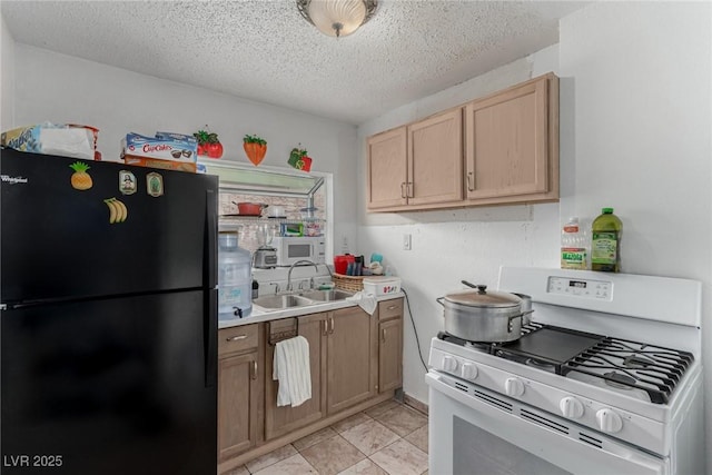 kitchen with gas range gas stove, freestanding refrigerator, a sink, light countertops, and a textured ceiling