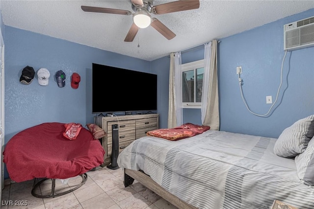 bedroom with a wall mounted air conditioner, a textured ceiling, ceiling fan, and a textured wall