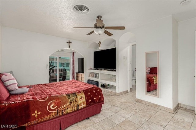 bedroom featuring visible vents, a textured ceiling, arched walkways, baseboards, and ceiling fan