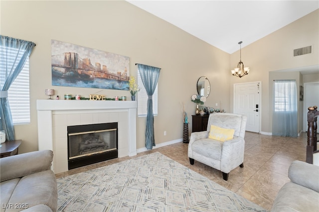 living room with baseboards, a chandelier, lofted ceiling, a tile fireplace, and tile patterned floors