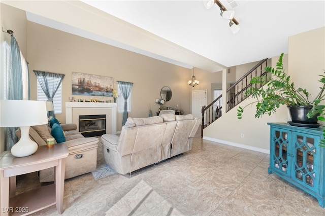 living area with a notable chandelier, stairway, baseboards, and a glass covered fireplace