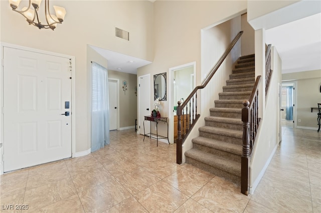 foyer with an inviting chandelier, stairway, baseboards, and visible vents