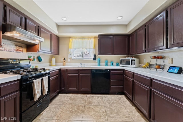 kitchen with black appliances, under cabinet range hood, a sink, tile countertops, and dark brown cabinetry