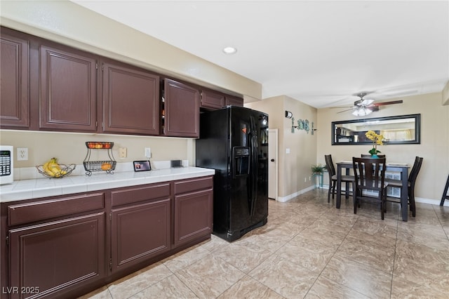 kitchen with baseboards, a ceiling fan, tile counters, and black refrigerator with ice dispenser