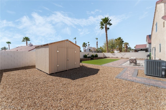 view of yard featuring central AC unit, a fenced backyard, an outdoor structure, a storage unit, and a patio area