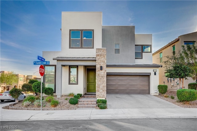 modern home featuring an attached garage, stucco siding, metal roof, driveway, and a standing seam roof