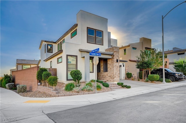 modern home featuring stone siding, stucco siding, and fence