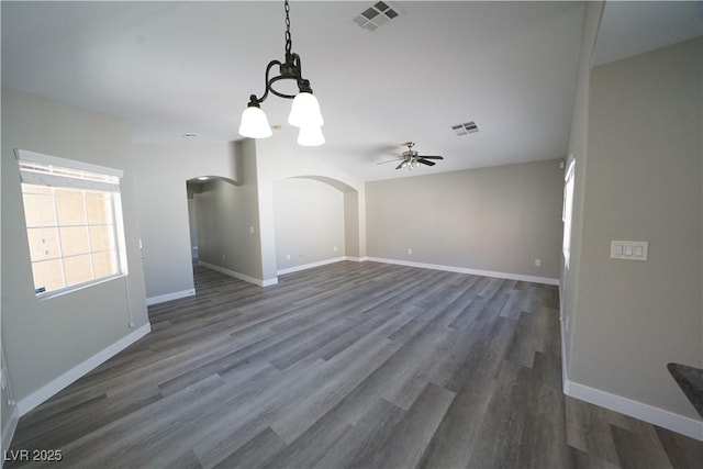 interior space featuring arched walkways, visible vents, baseboards, and wood finished floors