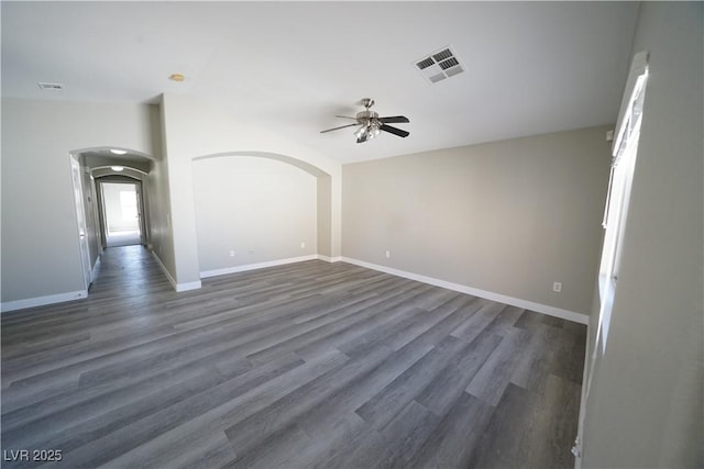 spare room with visible vents, baseboards, wood finished floors, arched walkways, and a ceiling fan