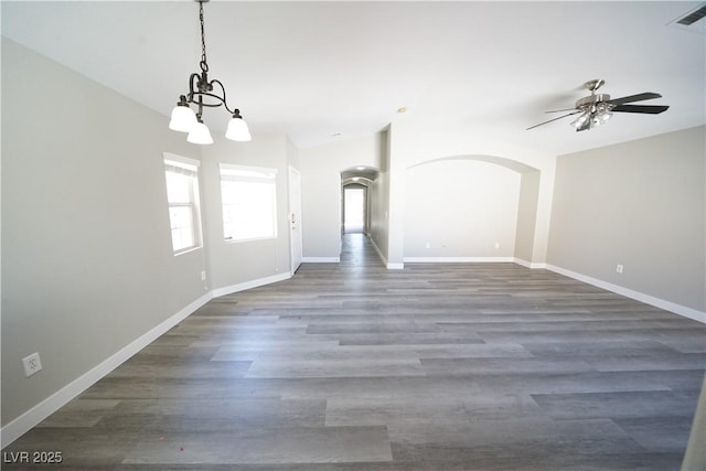 interior space with visible vents, arched walkways, baseboards, and dark wood-style floors