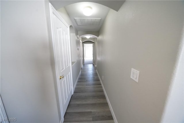 hall featuring arched walkways, visible vents, baseboards, and wood finished floors