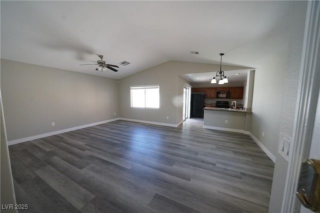 unfurnished living room with dark wood finished floors, visible vents, lofted ceiling, and a sink