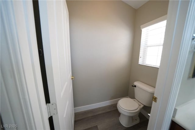 bathroom with toilet, wood finished floors, and baseboards