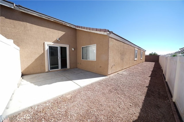 rear view of house featuring stucco siding, a fenced backyard, and a patio area