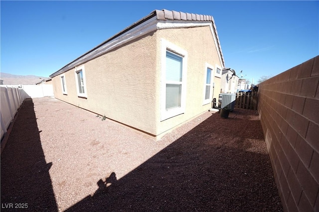 view of side of home with a patio, a fenced backyard, and stucco siding