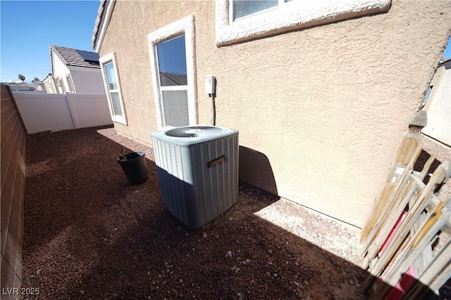 exterior details with stucco siding, cooling unit, and a fenced backyard