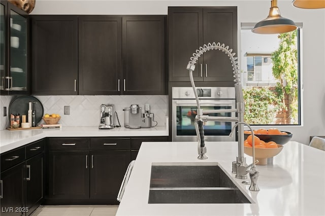 kitchen featuring glass insert cabinets, decorative backsplash, light countertops, and oven