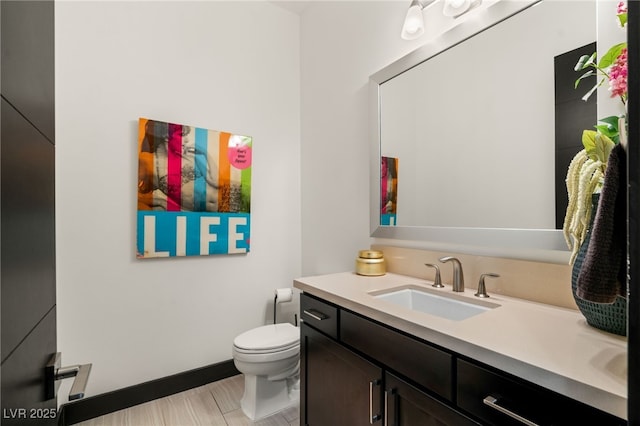 bathroom featuring toilet, vanity, and baseboards