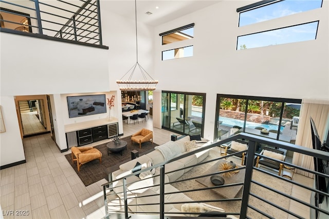 living room with an inviting chandelier, a high ceiling, and baseboards