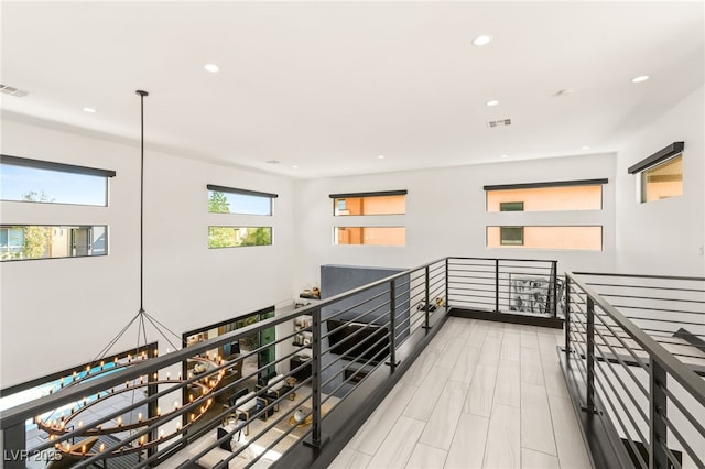 corridor with wood finished floors, recessed lighting, an upstairs landing, and visible vents