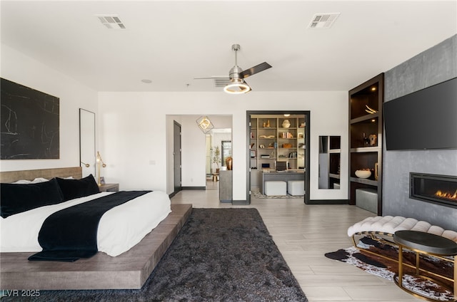 bedroom featuring visible vents, a large fireplace, a ceiling fan, and wood finished floors