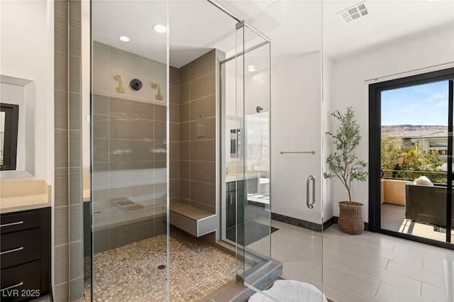 full bath with vanity, baseboards, visible vents, and a stall shower