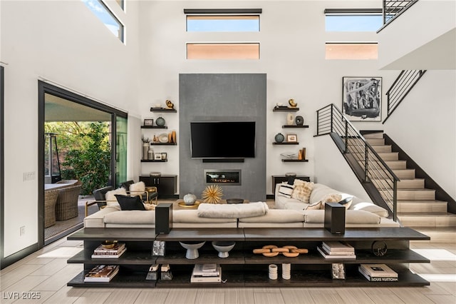 living area with stairway, a healthy amount of sunlight, wood finished floors, and a glass covered fireplace