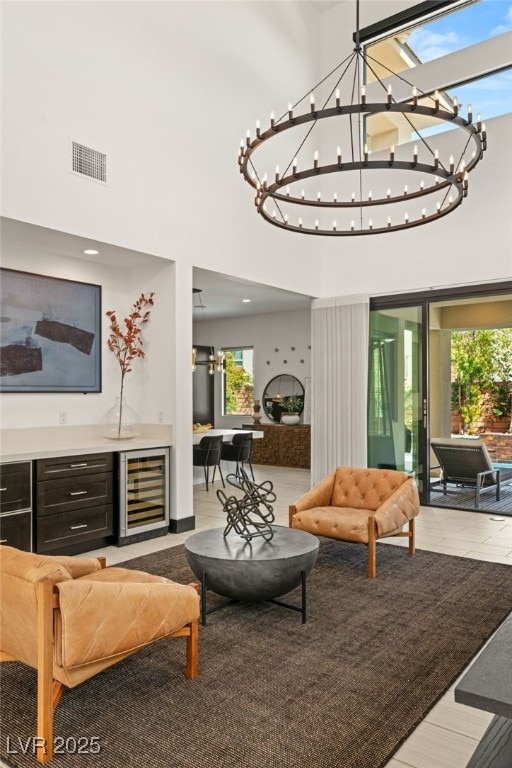 living area with beverage cooler, visible vents, and a towering ceiling