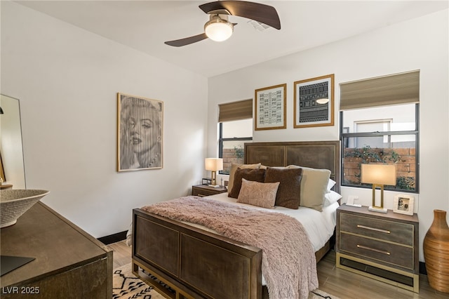 bedroom with multiple windows, ceiling fan, and light wood finished floors