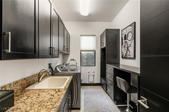 kitchen with dark cabinets, separate washer and dryer, light wood-style flooring, and a sink