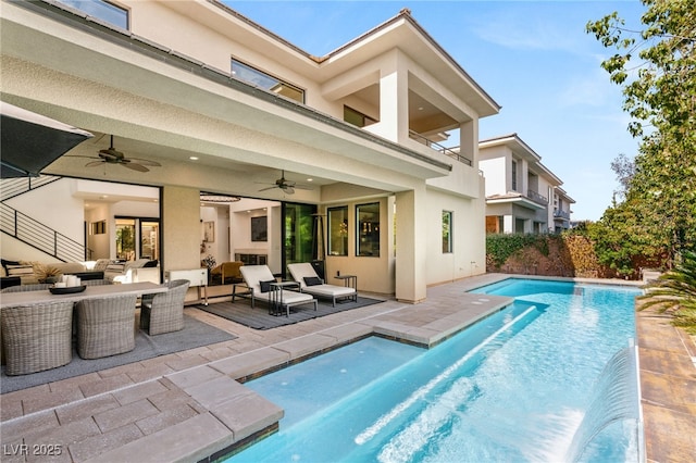 back of house featuring outdoor lounge area, a patio area, a fenced in pool, and stucco siding