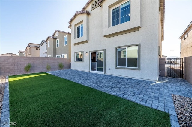 back of house with stucco siding, a yard, a fenced backyard, and a patio area