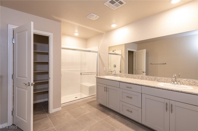 bathroom with double vanity, visible vents, a stall shower, and a sink