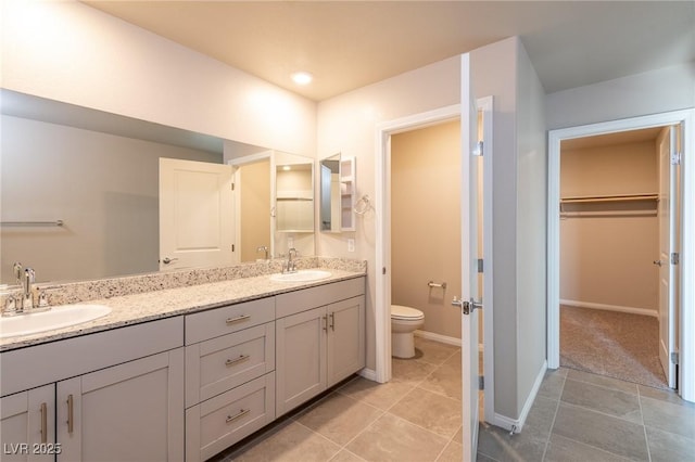 full bathroom featuring double vanity, a spacious closet, toilet, and a sink